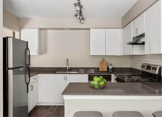 A kitchen with a refrigerator, stove, and sink.