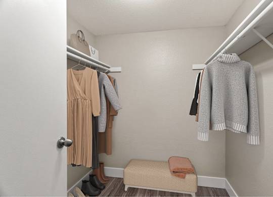 A small closet with a bench and clothes hanging.