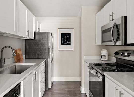 A kitchen with white cabinets and a black refrigerator.