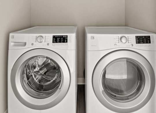 Two white front loading washing machines in a laundry room.
