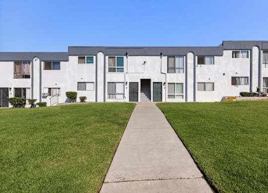A long white building with a walkway in front.