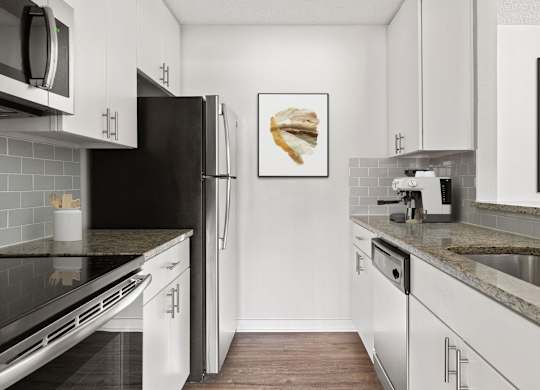 A kitchen with white cabinets and a black refrigerator.