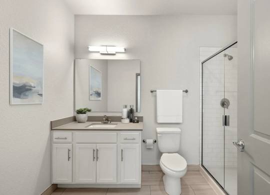 A white bathroom with a toilet, sink, and a mirror.