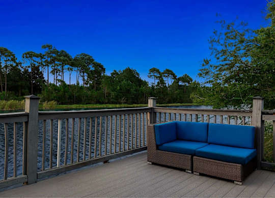 A blue couch is on a wooden deck with a railing.