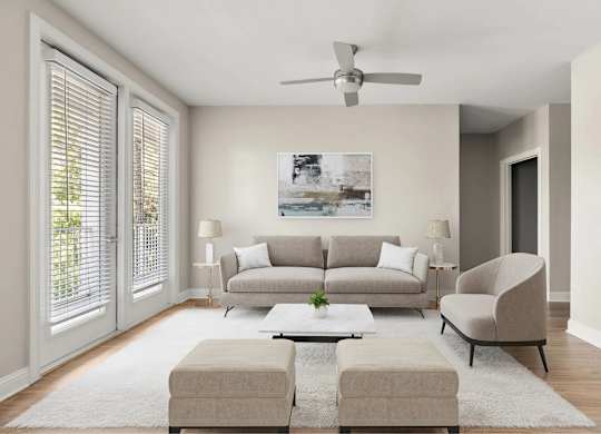 A living room with a grey couch, a white rug, and a ceiling fan.