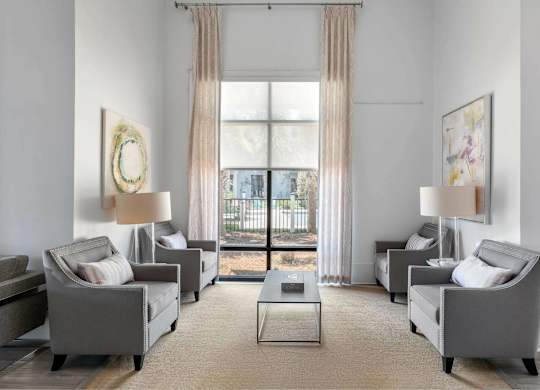 A living room with grey couches and a large window.