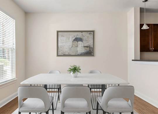 A dining room with a white table and chairs.
