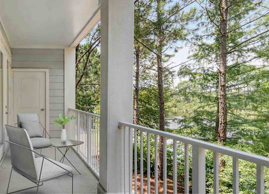 A balcony with chairs facing trees.