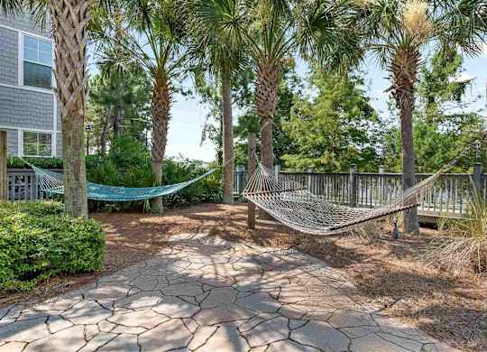 A hammock is strung between two wooden posts in a backyard.