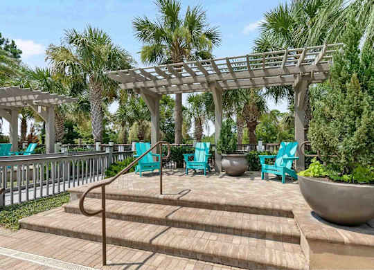 A wooden deck with a pergola and blue chairs.