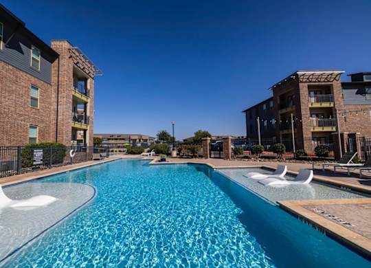 A swimming pool in front of a brick building.