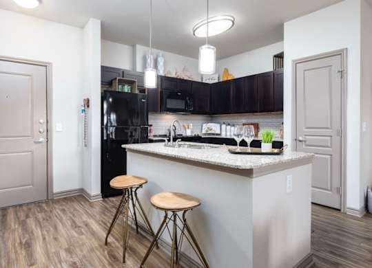A kitchen with a white island and black appliances.