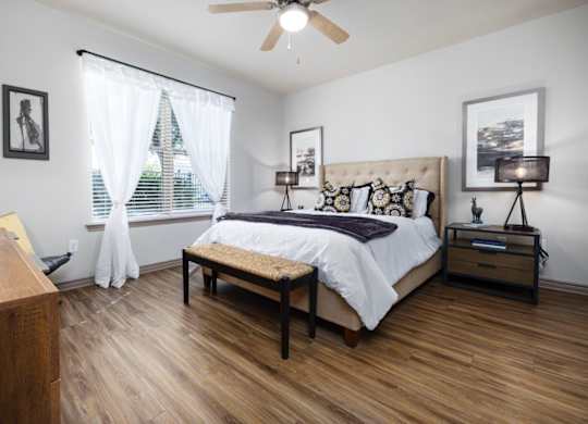 A bedroom with a bed, nightstand, and window.