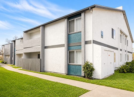 A white apartment building with a green door and a grey fence.