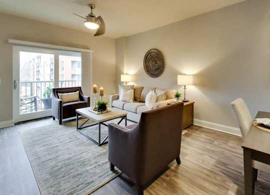 A living room with a brown couch, a coffee table, and a dining table with chairs.