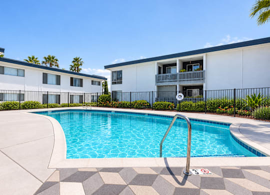 A swimming pool in front of a building with a metal fence.