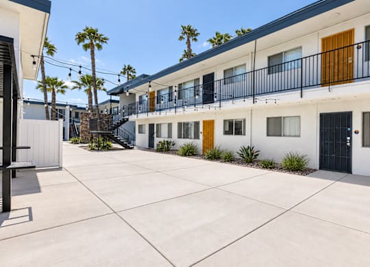 A sunny day at a white building with black railings and yellow doors.