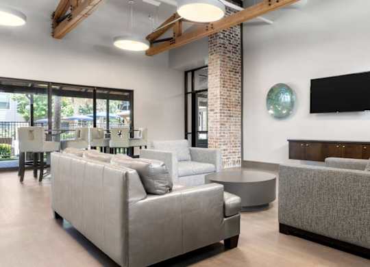 A living room with a grey couch and a flat screen TV mounted on the wall.