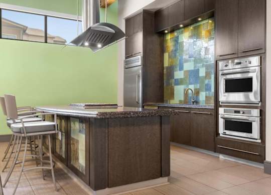 A modern kitchen with a green wall and a wooden island.
