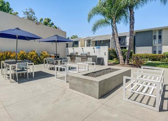 A patio with a table, chairs, and umbrellas.