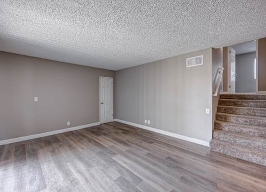 A room with wooden flooring and a staircase.