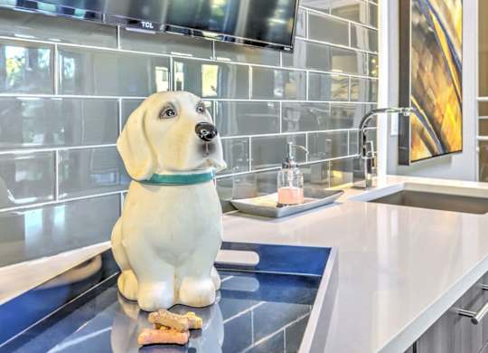 A dog statue is sitting on a countertop in a modern kitchen.