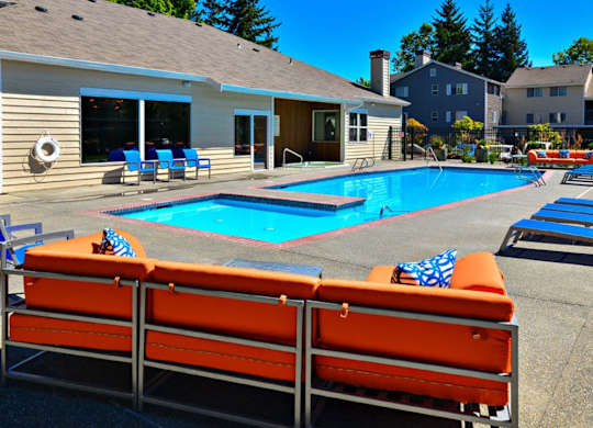 A poolside area with orange sun loungers and a clear blue sky.