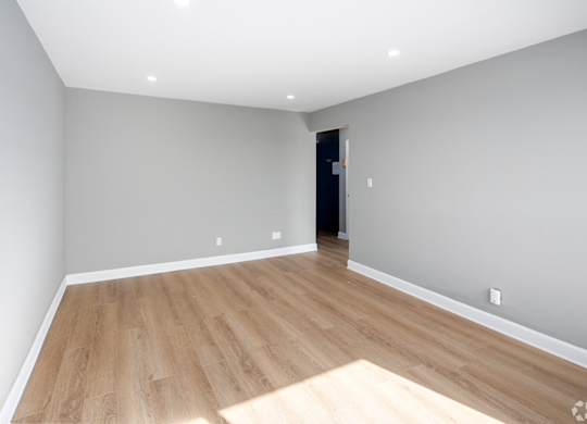 A room with wooden flooring and a door in the background.