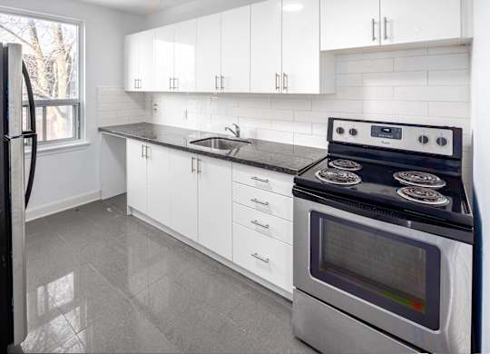 A modern kitchen with a black stove top oven and white cabinets.