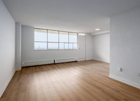 A room with wooden flooring and a window with a view of the outside.