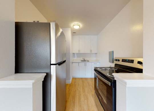 A kitchen with a black refrigerator and a white oven.