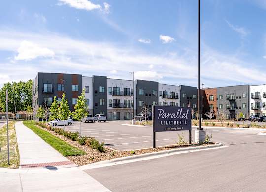 The image shows a modern building complex with a sign that reads