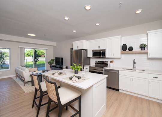 A modern kitchen with white cabinets and a dining table.