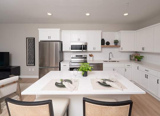A modern kitchen with a dining table set for two.