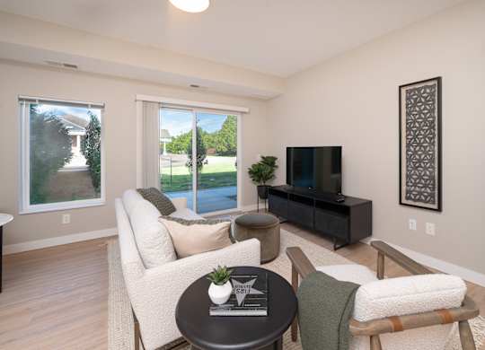 A living room with a white couch, a black coffee table, and a flat screen TV.