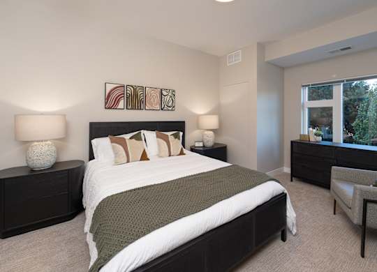 A bedroom with a large bed and a chair.