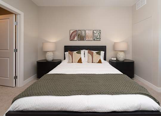 A bed with a green blanket and a white comforter is in the center of the image.