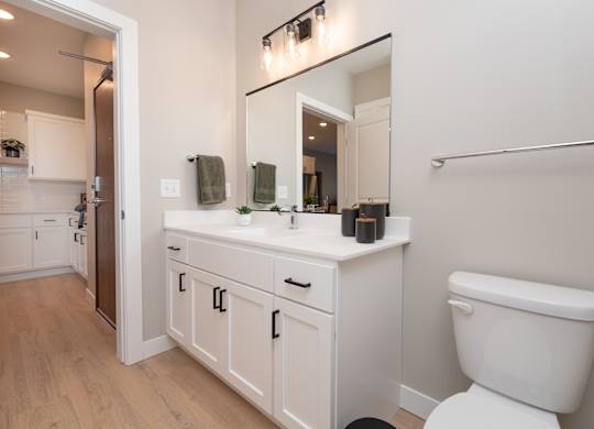 A white bathroom with a toilet, sink, and mirror.