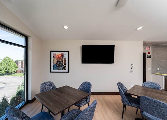A conference room with a table, chairs, and a TV mounted on the wall.