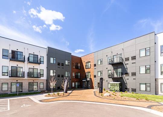A modern apartment complex with a parking lot in front.