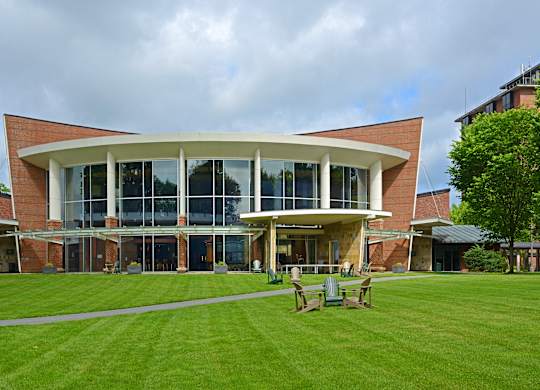 A modern building with a curved glass wall and a brick facade.