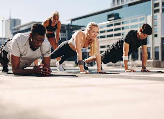 A group of people doing push-ups outdoors.