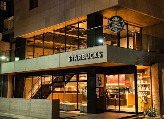 A Starbucks storefront at night with lights on inside.
