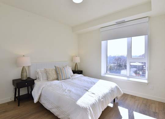 A bedroom with a large bed and two lamps on side tables at Roxy Apartments, Ontario