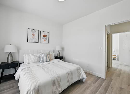 A bedroom with a large bed and two nightstands with lamps at Roxy Apartments, Hamilton, Ontario