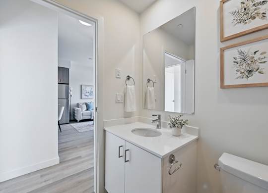 A white bathroom with a sink, mirror, and a bathtub at Roxy Apartments, Ontario