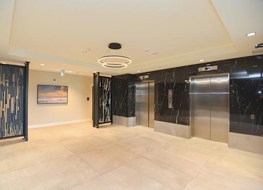 A spacious lobby with marble floors and a modern art piece on the wall at Roxy Apartments, Ontario