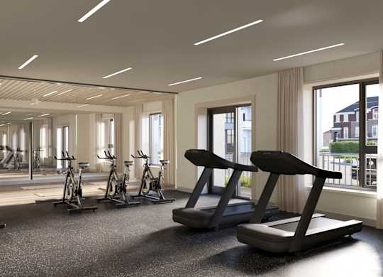 A spacious gym with treadmills, exercise bikes, and a view of the city at Roxy Apartments, Hamilton, ON