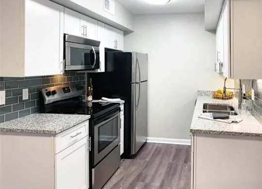 A kitchen with black appliances and white cabinets. at Latitude at Riverchase, Hoover, AL, 35216