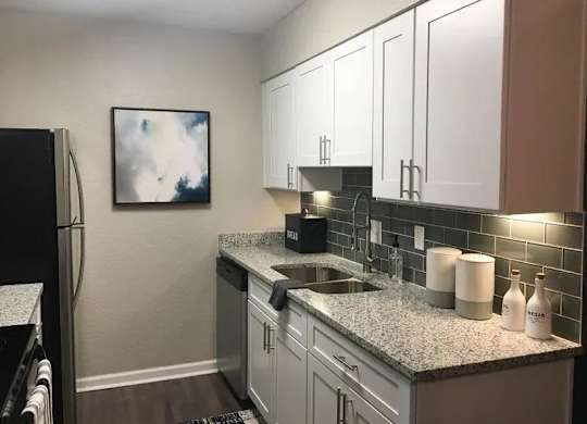 A kitchen with a black refrigerator and white cabinets. at Latitude at Riverchase, Hoover, AL, 35216